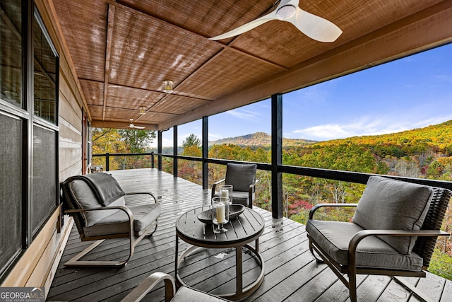 sunroom / solarium with a mountain view, ceiling fan, and wooden ceiling