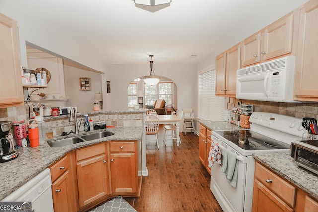 kitchen featuring decorative backsplash, a peninsula, white appliances, a sink, and dark wood-style floors