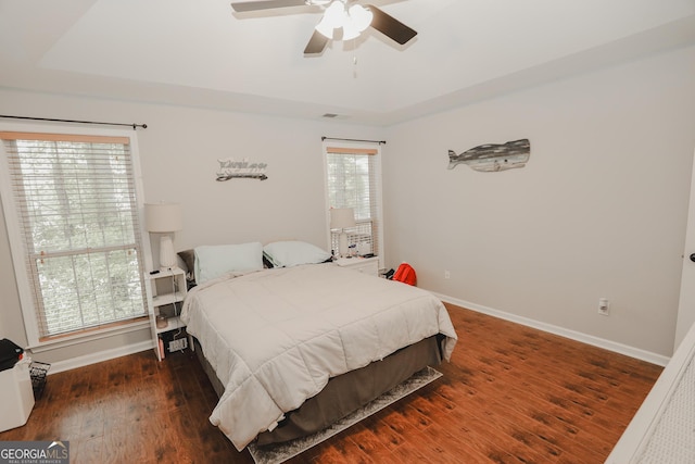 bedroom featuring a tray ceiling, baseboards, visible vents, and hardwood / wood-style floors