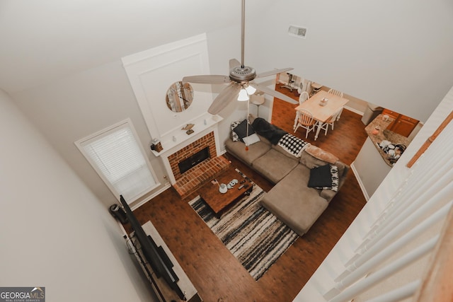 living area featuring a brick fireplace, visible vents, lofted ceiling, and ceiling fan