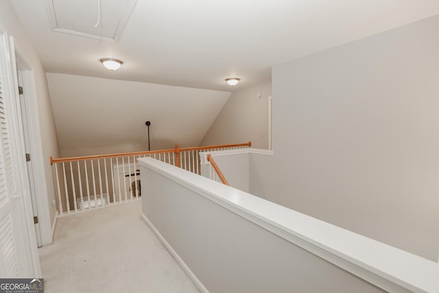 corridor featuring attic access, light colored carpet, vaulted ceiling, and an upstairs landing