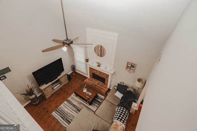 living room featuring ceiling fan, dark hardwood / wood-style floors, and a brick fireplace