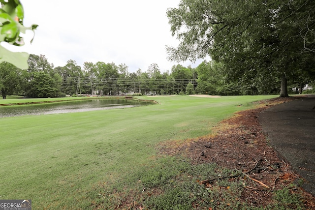 surrounding community with a water view and a lawn