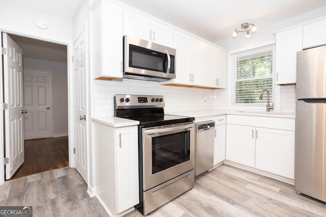 kitchen with appliances with stainless steel finishes, light hardwood / wood-style floors, and white cabinetry