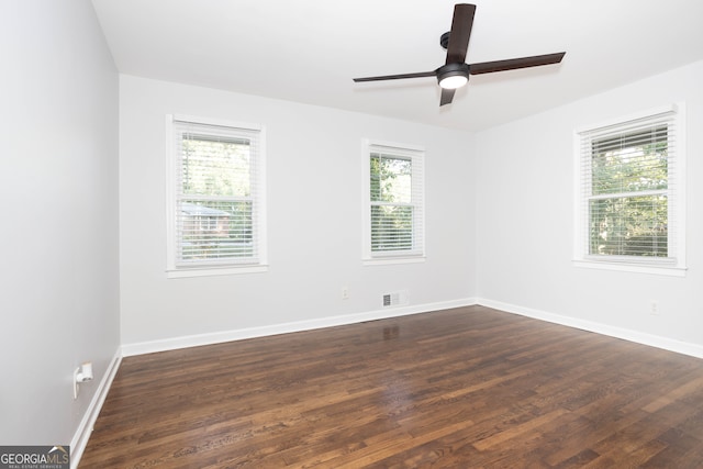 empty room with dark hardwood / wood-style flooring, ceiling fan, and a wealth of natural light