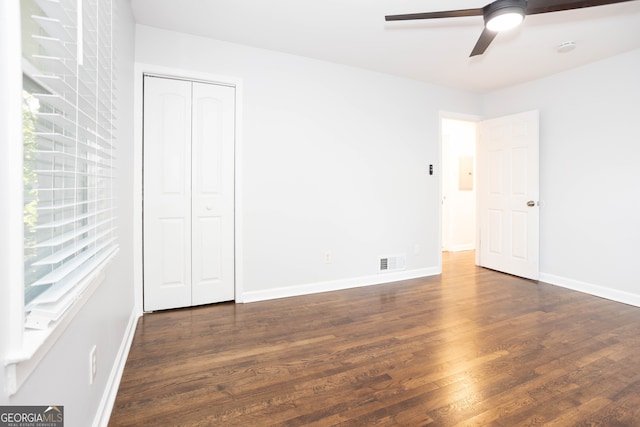 unfurnished bedroom with ceiling fan, dark wood-type flooring, and a closet