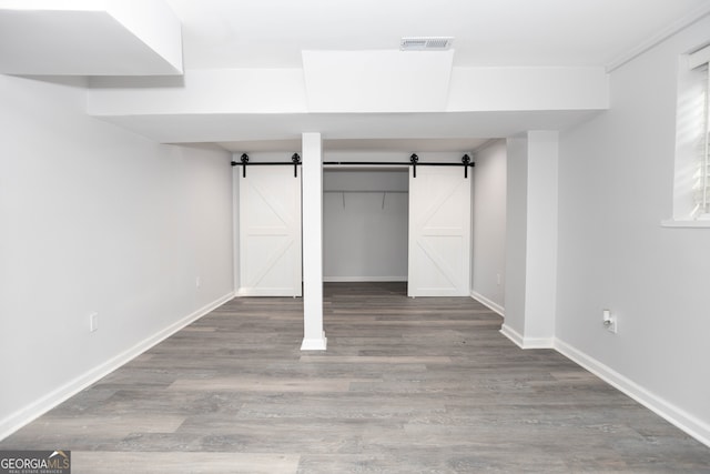 unfurnished bedroom with a closet, hardwood / wood-style flooring, and a barn door