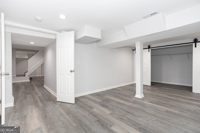 basement featuring dark wood-type flooring and a barn door