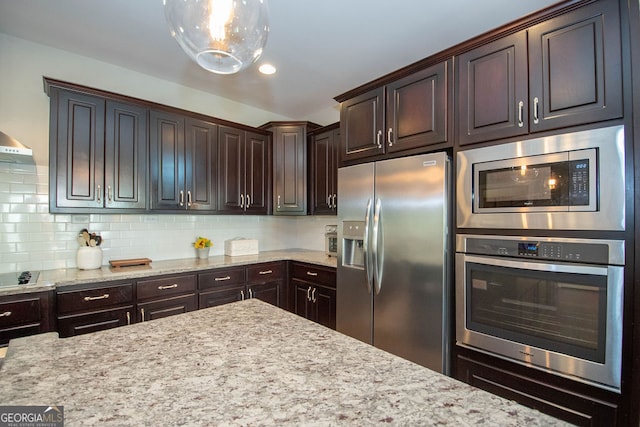 kitchen featuring dark brown cabinets, stainless steel appliances, and light stone countertops