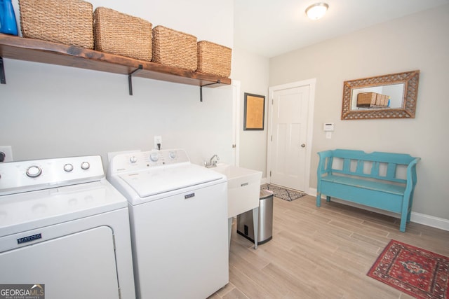 laundry area with washing machine and dryer, sink, and light hardwood / wood-style floors