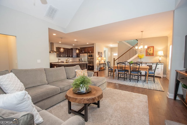 living room featuring high vaulted ceiling, hardwood / wood-style flooring, and an inviting chandelier