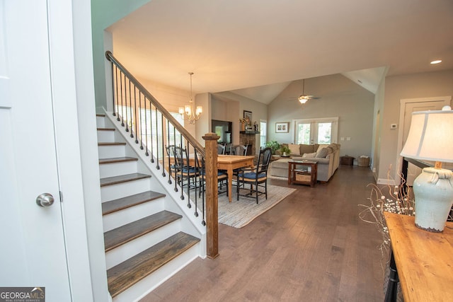 foyer with ceiling fan with notable chandelier, dark hardwood / wood-style flooring, and vaulted ceiling