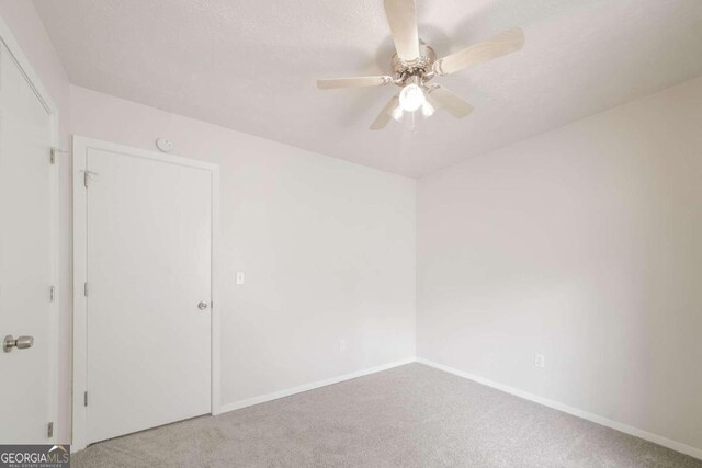 carpeted spare room featuring a textured ceiling, baseboards, and a ceiling fan