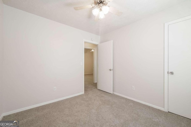 unfurnished bedroom featuring baseboards, light colored carpet, ceiling fan, and a textured ceiling