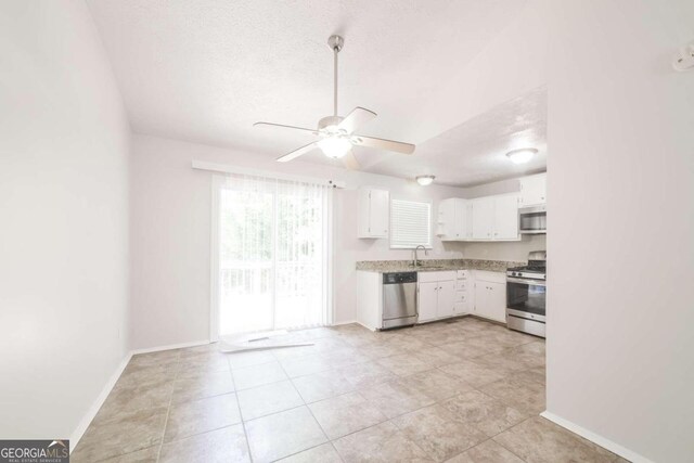 kitchen featuring a textured ceiling, stainless steel appliances, sink, white cabinetry, and ceiling fan