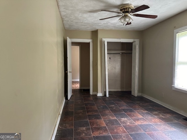 unfurnished bedroom with a closet, multiple windows, ceiling fan, and a textured ceiling