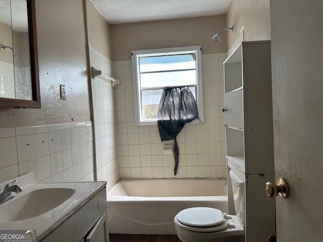 full bathroom with tiled shower / bath, vanity, a textured ceiling, backsplash, and toilet