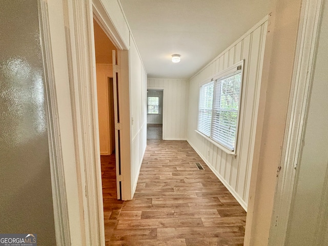 hallway with ornamental molding and light hardwood / wood-style floors