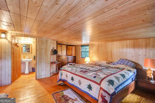 bedroom featuring wooden ceiling, sink, wooden walls, and light hardwood / wood-style floors