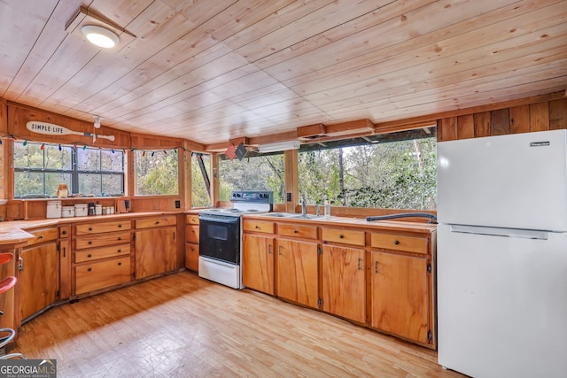 kitchen featuring wooden walls, wooden ceiling, white appliances, light hardwood / wood-style floors, and sink