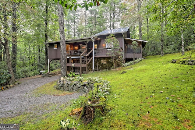 view of front facade with a front yard, a sunroom, and a wooden deck