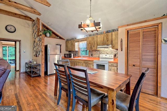 dining area featuring hardwood / wood-style flooring, an inviting chandelier, sink, high vaulted ceiling, and beam ceiling