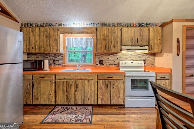 kitchen featuring a textured ceiling, dark hardwood / wood-style floors, appliances with stainless steel finishes, and decorative backsplash