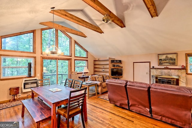 dining room featuring light hardwood / wood-style flooring, heating unit, beamed ceiling, and a fireplace