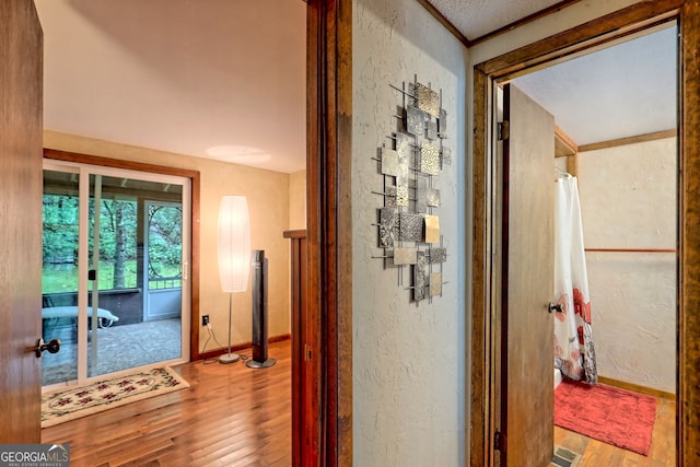 hall with wood-type flooring and crown molding