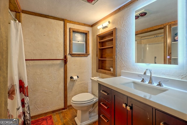 bathroom with toilet, vanity, a textured ceiling, curtained shower, and wood-type flooring