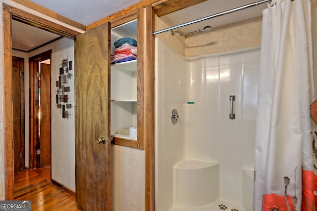 bathroom featuring curtained shower, hardwood / wood-style flooring, and a textured ceiling