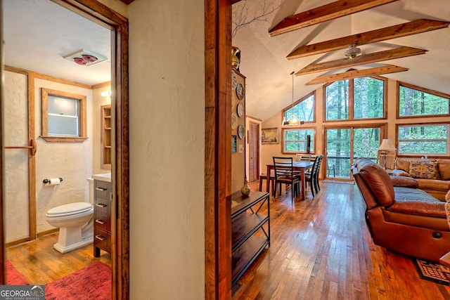 interior space with wood-type flooring and vaulted ceiling with beams