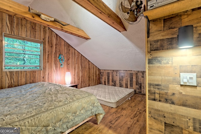 bedroom featuring lofted ceiling, wood walls, wood-type flooring, and a textured ceiling