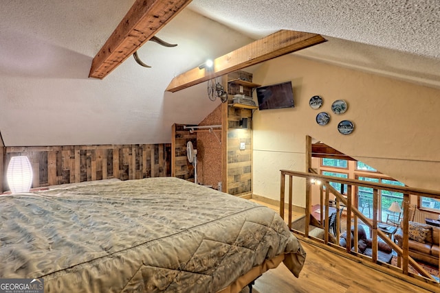 bedroom featuring multiple windows, wood-type flooring, lofted ceiling with beams, and a textured ceiling