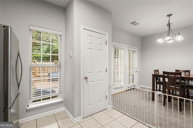 tiled foyer with an inviting chandelier and a healthy amount of sunlight