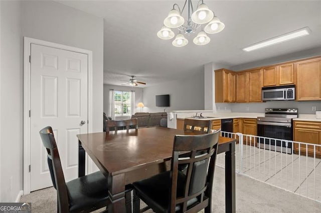 carpeted dining space with ceiling fan with notable chandelier and sink