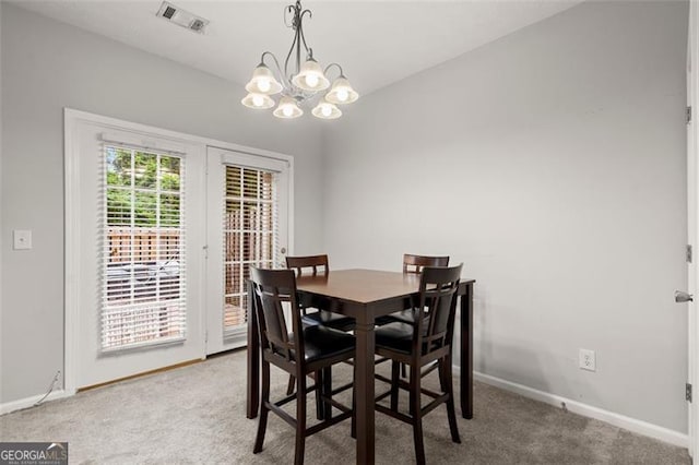 dining space featuring carpet flooring and a notable chandelier