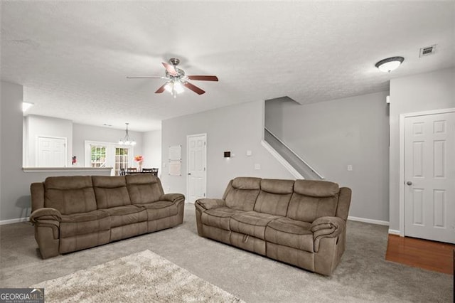 carpeted living room with a textured ceiling and ceiling fan with notable chandelier