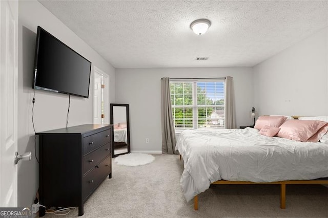 bedroom featuring a textured ceiling and light colored carpet