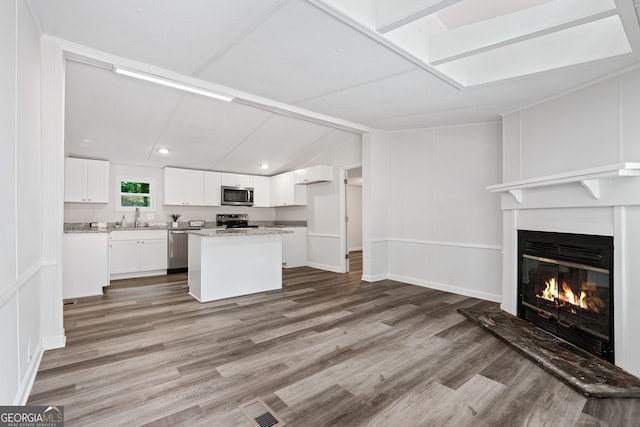 kitchen featuring stainless steel appliances, white cabinetry, a kitchen island, and hardwood / wood-style flooring