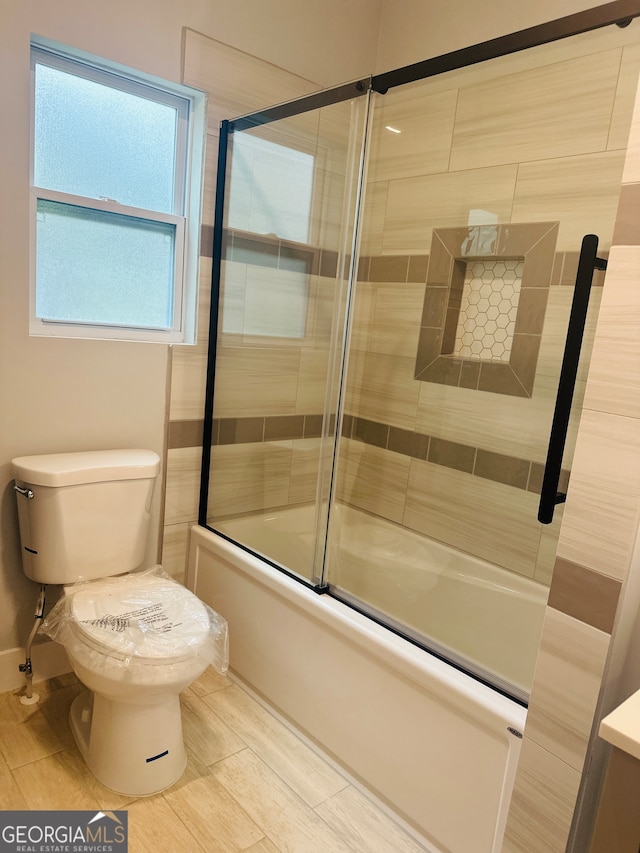 bathroom featuring bath / shower combo with glass door and toilet