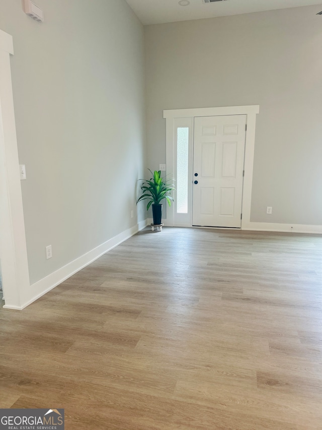 foyer entrance featuring light hardwood / wood-style flooring and a high ceiling