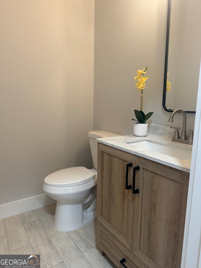 bathroom with hardwood / wood-style floors, vanity, and toilet