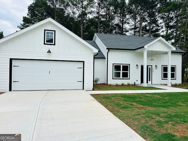 modern inspired farmhouse with a garage and a front lawn