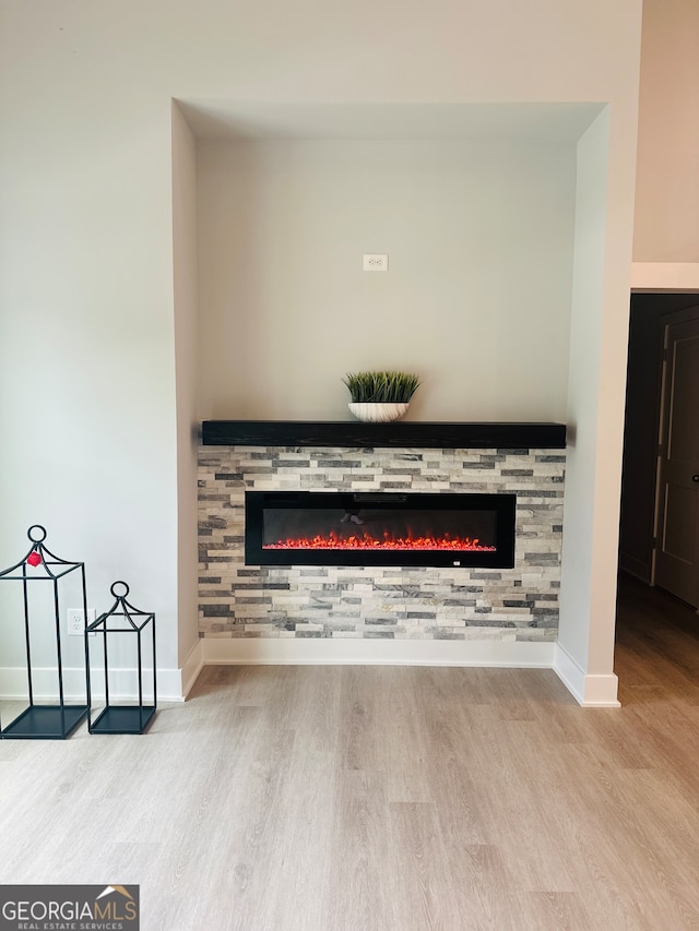 details with wood-type flooring and a stone fireplace