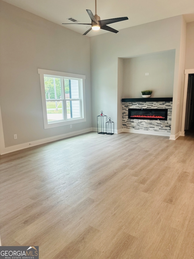 unfurnished living room featuring ceiling fan, a fireplace, and light hardwood / wood-style flooring