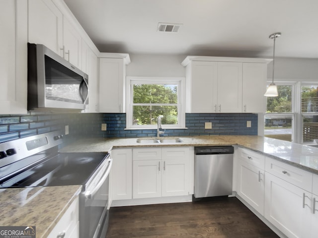 kitchen with appliances with stainless steel finishes, sink, white cabinets, hanging light fixtures, and light stone countertops