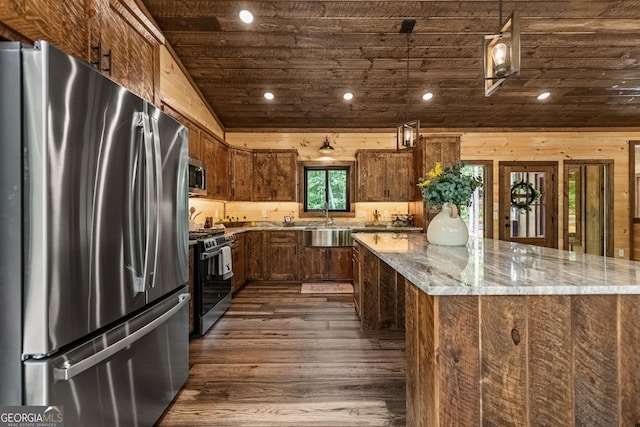 kitchen featuring dark hardwood / wood-style floors, a spacious island, light stone counters, and stainless steel appliances