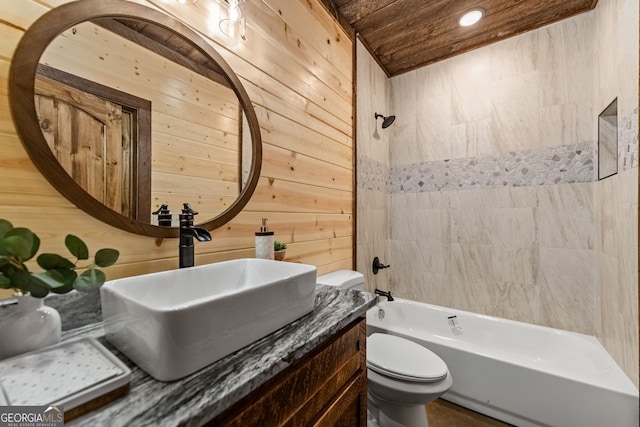 full bathroom with vanity, wooden ceiling, wooden walls, tiled shower / bath combo, and toilet