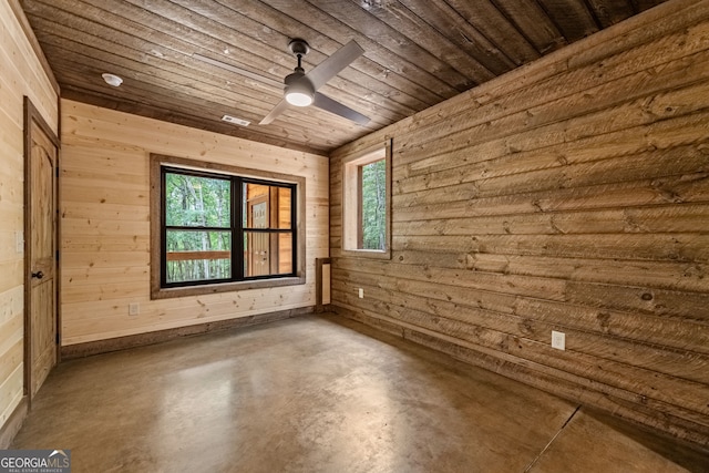 unfurnished room featuring concrete flooring, a wealth of natural light, wooden ceiling, and wood walls